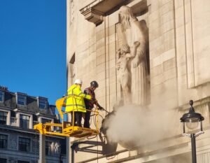Tradesman cleaning statue on building facade